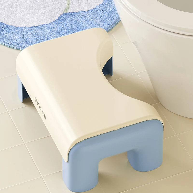 Beige and blue step toilet stool next to a toilet on a tiled floor.
