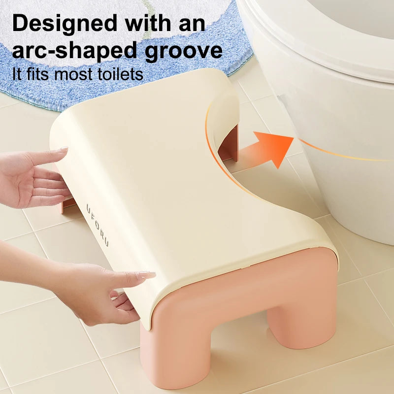 Beige stool with arc-shaped groove fitting most toilets, on a bathroom floor.
