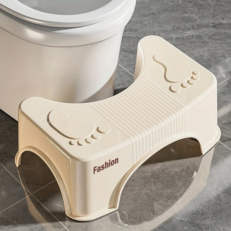 Beige toilet stool with 'Fashion' branding next to a toilet on a tiled bathroom floor.