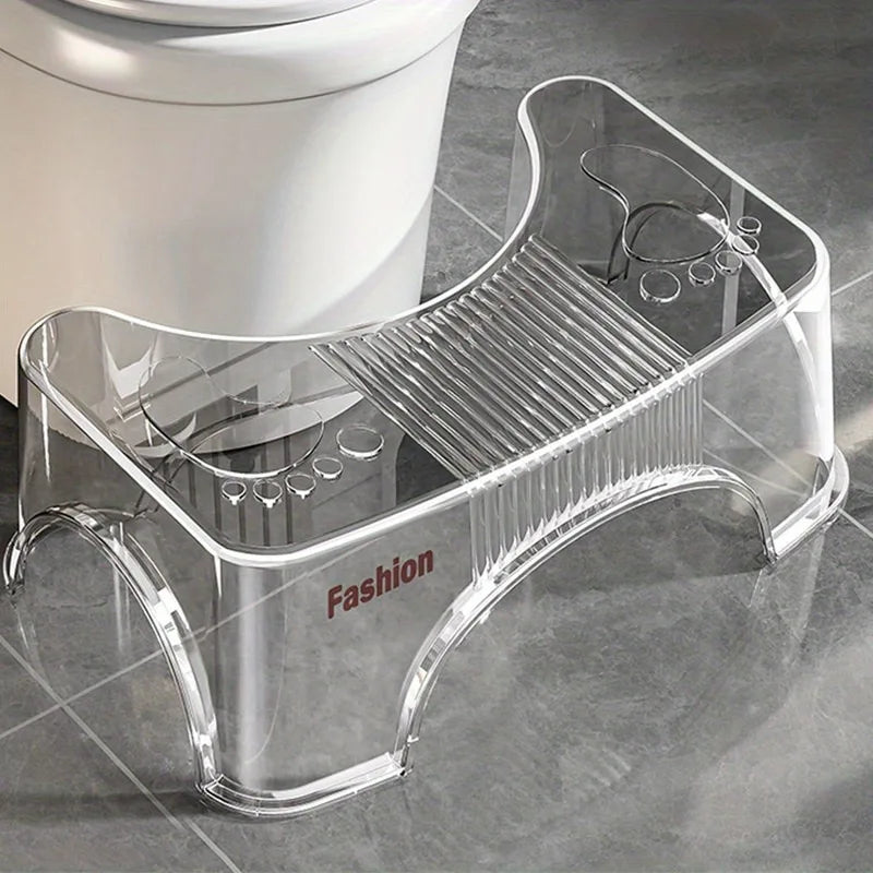 Clear toilet stool with 'Fashion' label next to a toilet on a tiled floor