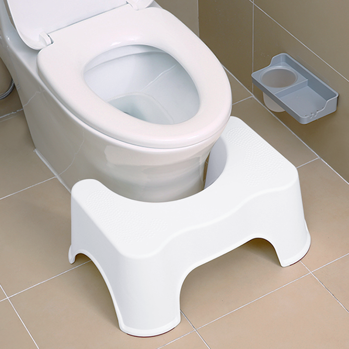 White step stool in front of a toilet on a tiled bathroom floor.