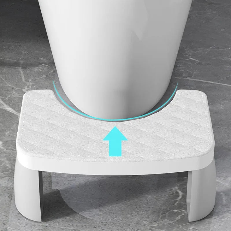 White toilet stool with blue arrows next to a toilet on a gray marble floor