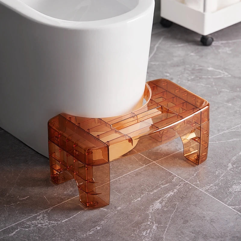 Transparent orange step stool in front of a white toilet
