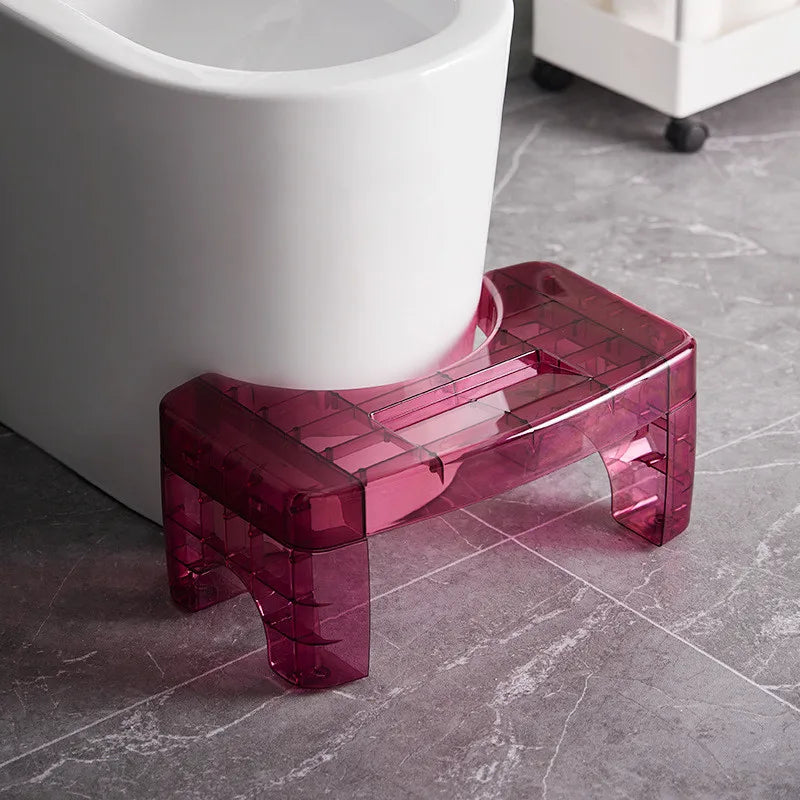 Transparent red step stool next to a white toilet